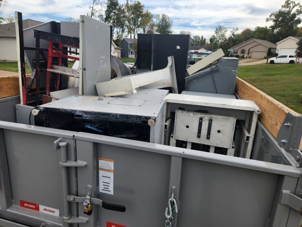Dump trailer packed with metal scraps, broken furniture, and miscellaneous debris from a large junk haul.