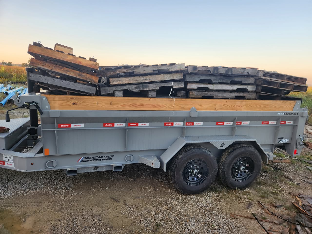 Dump trailer carrying a large load of weathered wooden pallets, ready for junk removal transport.