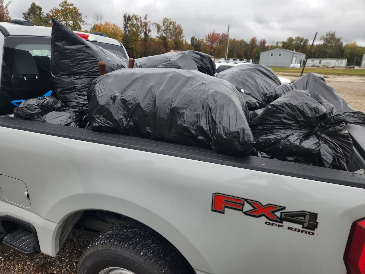 Pickup truck bed filled with large black trash bags after a junk removal and hauling job.